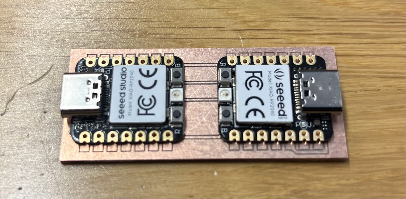 Freshly milled copper-clad PCB sitting on the Roland SRM-20 bed, showing two XIAO RP2040 footprints with cleanly isolated traces