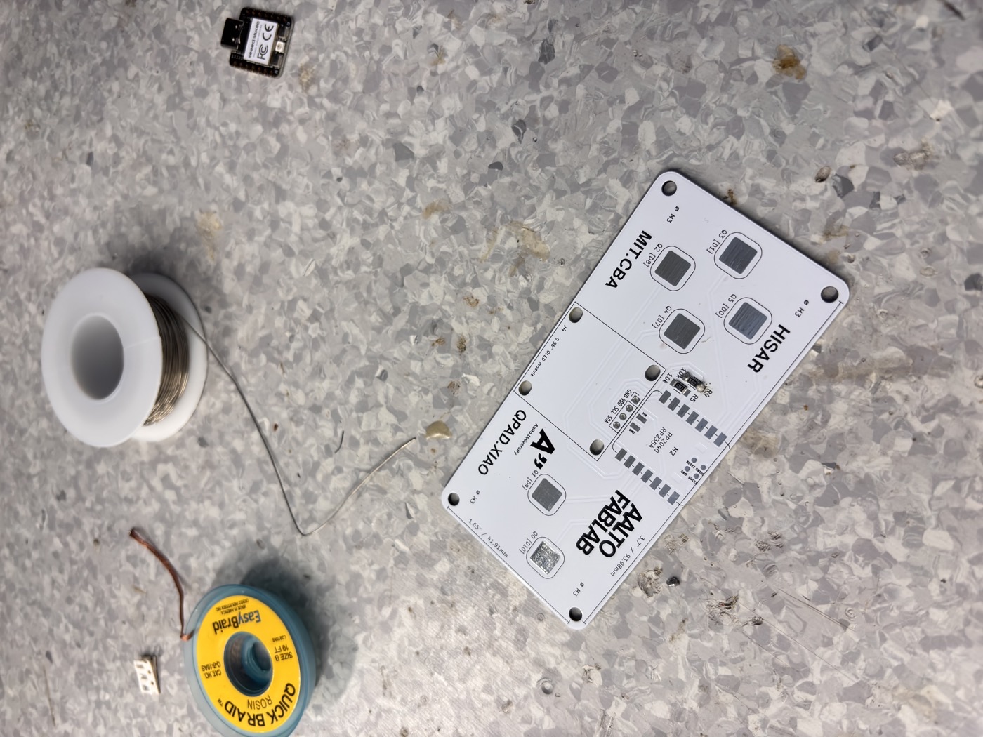 QPAD board during soldering — SMD components placed, iron being applied to the pads