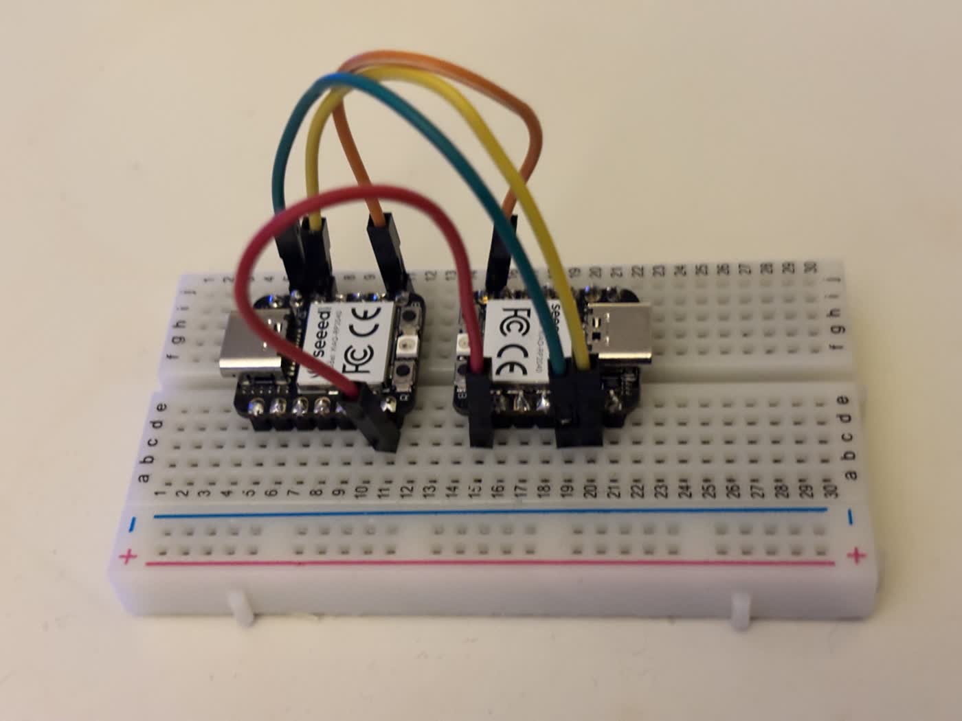 Two Seeed XIAO RP2040 microcontroller modules mounted on a breadboard connected by jumper wires for an initial wiring test