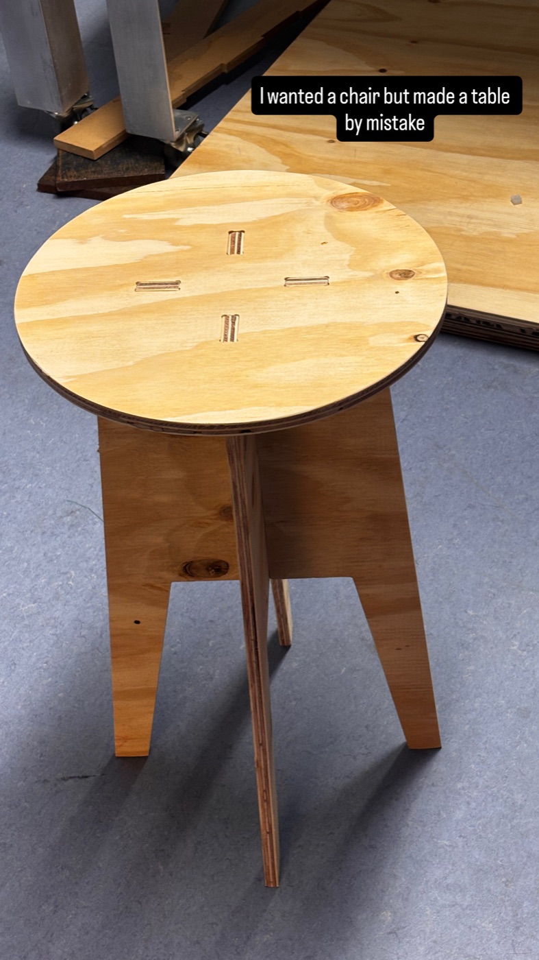 Final assembled three-leg plywood side table standing on the floor of the Fablab