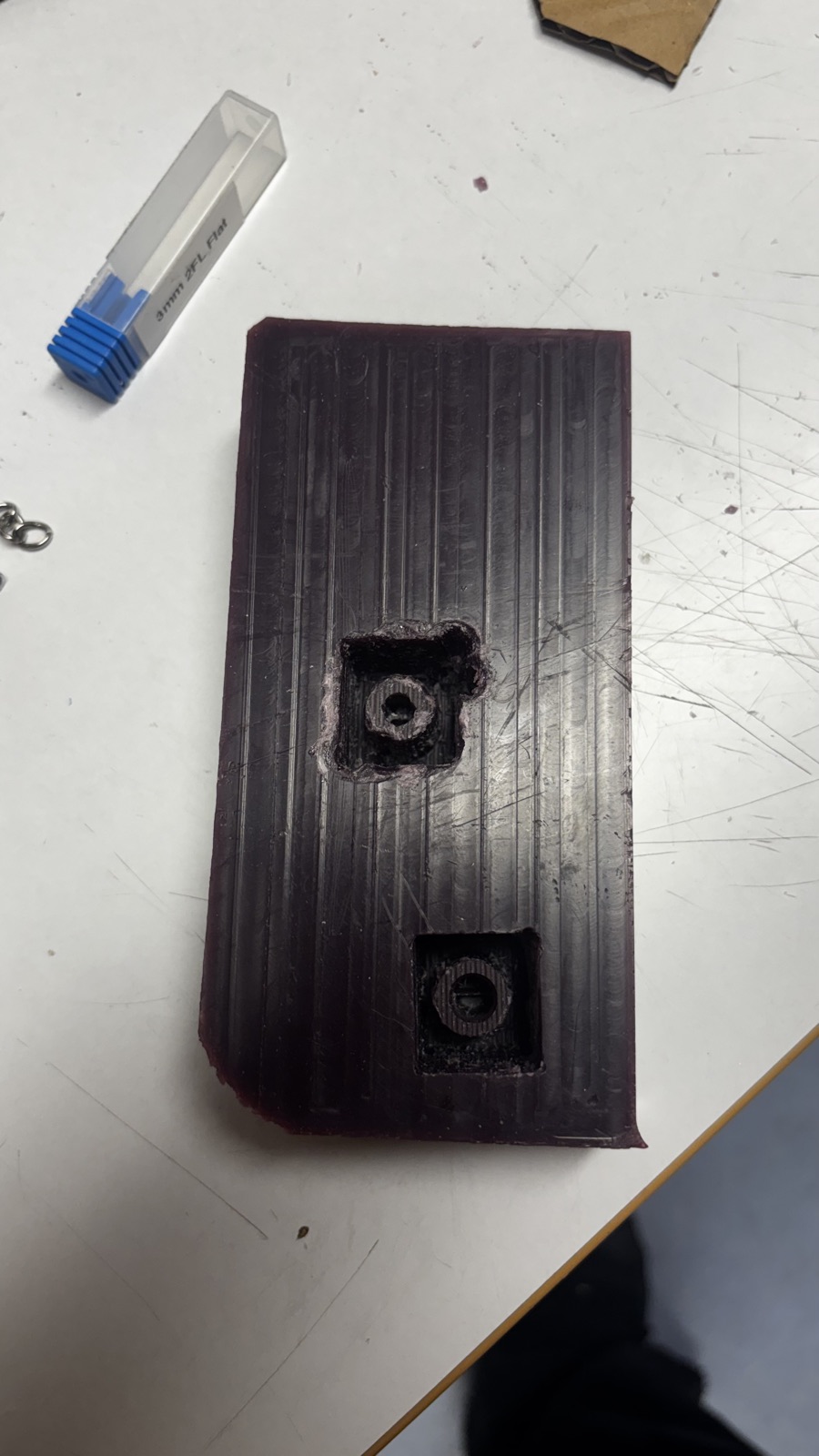 The wax block on a table with both milled cavities, the first one rough around the rim and the second one clean