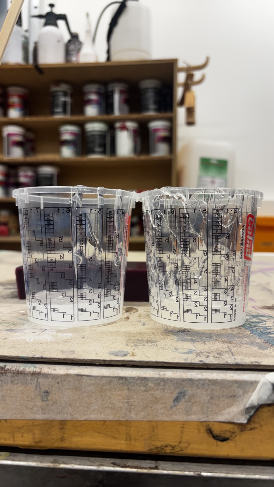 Two graduated mixing cups side by side with equal amounts of clear silicone in each