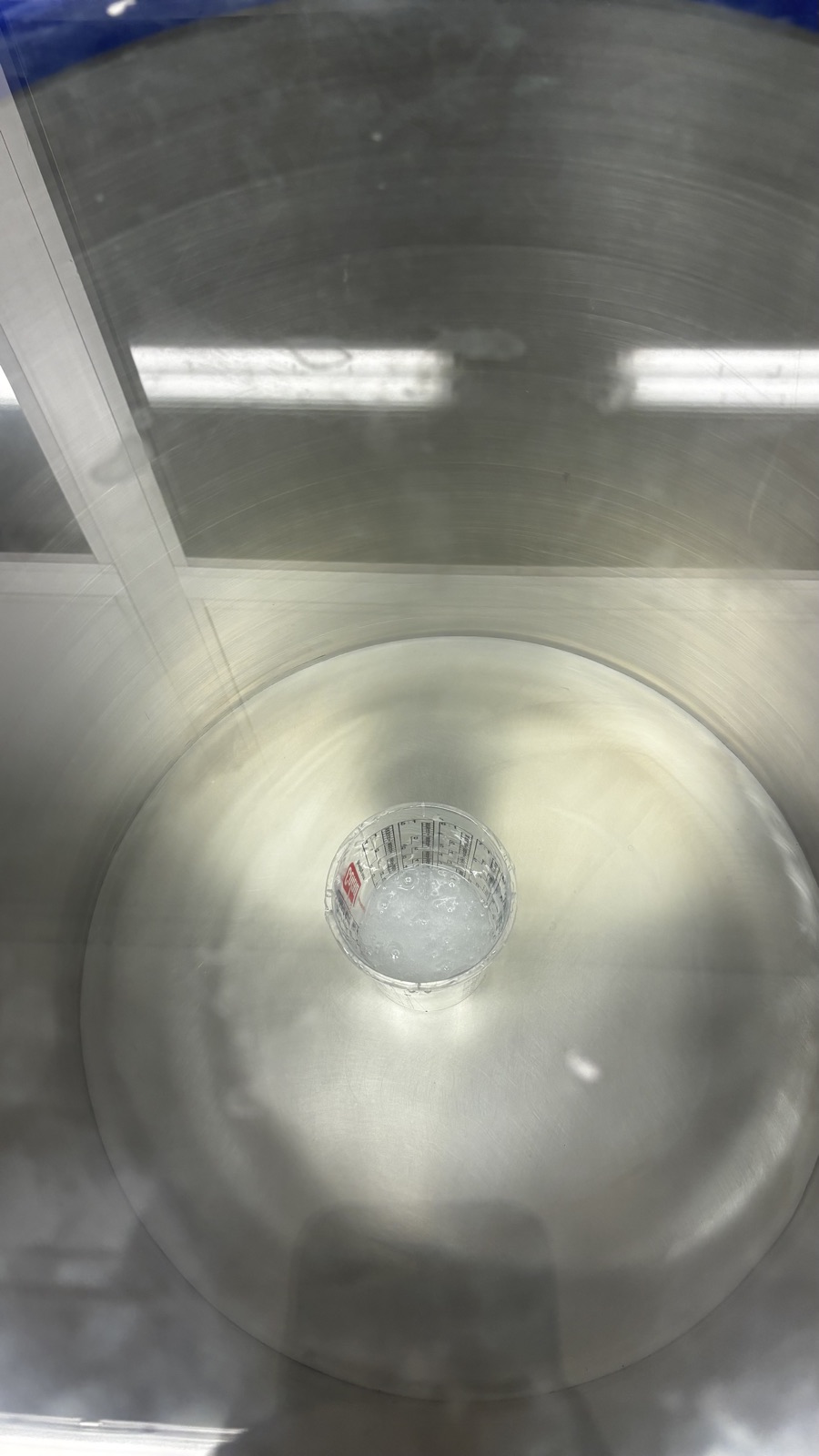 The mixing cup with silicone sitting on the plate inside the vacuum chamber, seen through the glass lid