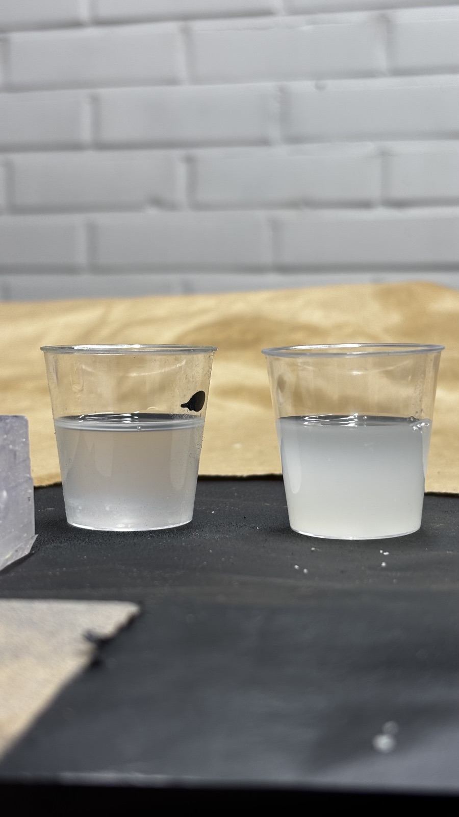 Close view of the two cups side by side, the left resin water clear with a slight tint, the right one opaque milky white