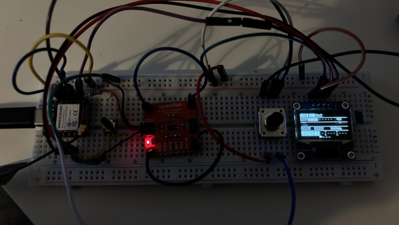 Breadboard prototype with the XIAO ESP32-S3 Sense, the VL53L4CD ToF breakout, a rotary encoder with a red cap, a tactile button and a 0.96 inch OLED that reads USB CC Ch2, DST CC23 CC22, 142mm