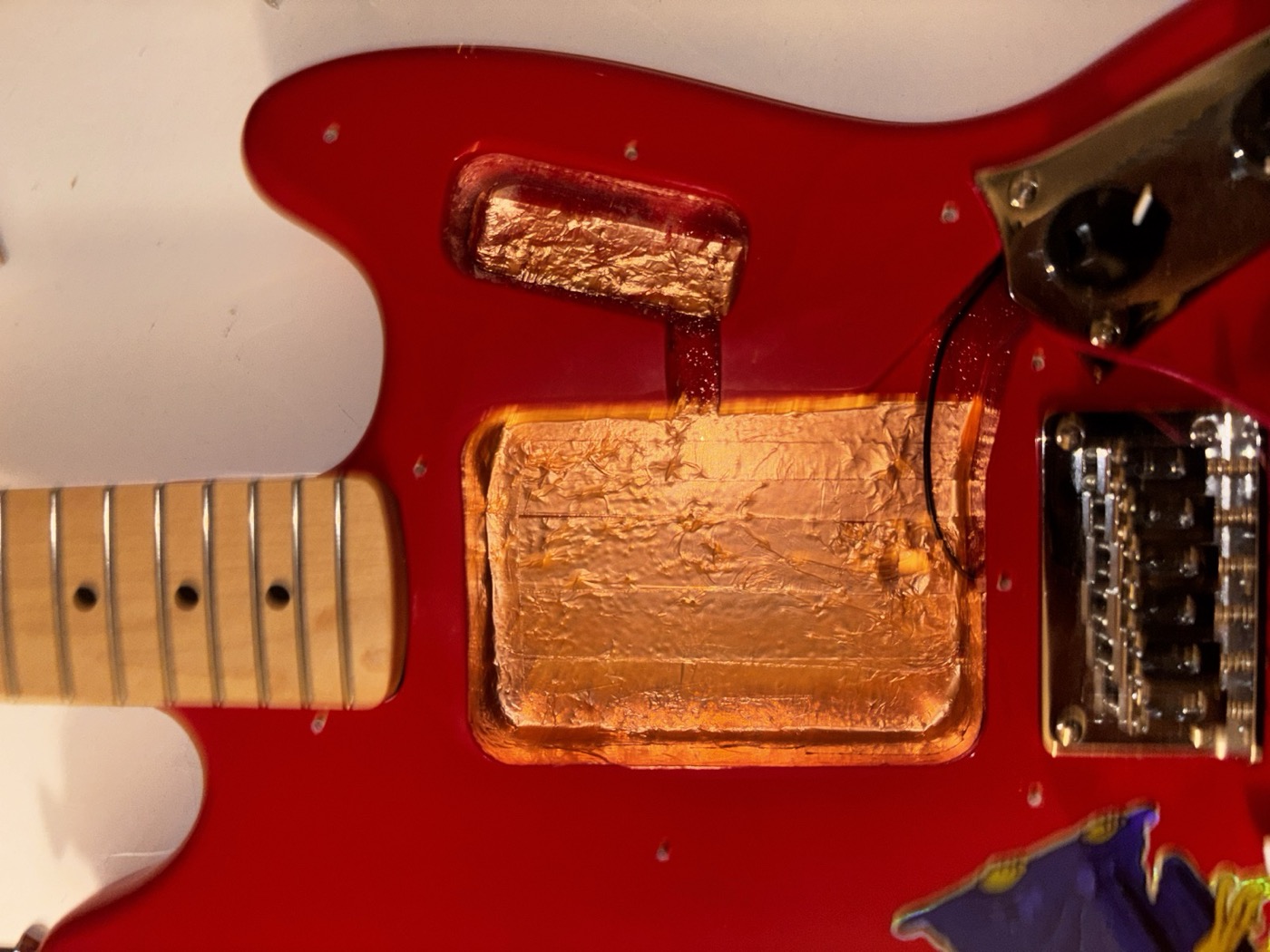 Inside of the Squier Mustang body cavity, fully lined with copper foil tape that has been soldered along all the seams