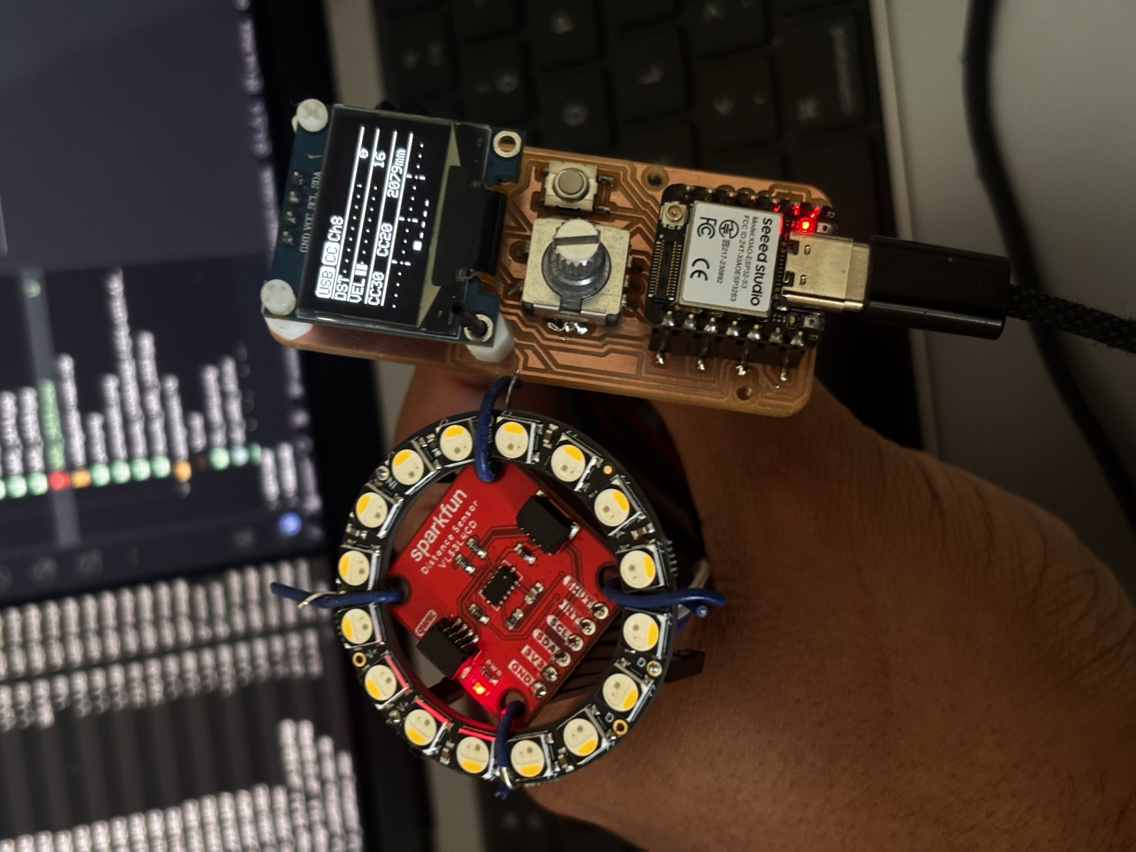 Last version of the milled MIDI controller board with the XIAO ESP32-S3, OLED screen, rotary encoder and ToF sensor populated, sitting on the workbench