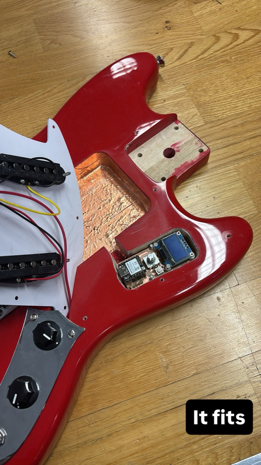 The guitar body lying flat with the controller board seated flush in its pocket, pickguard set aside
