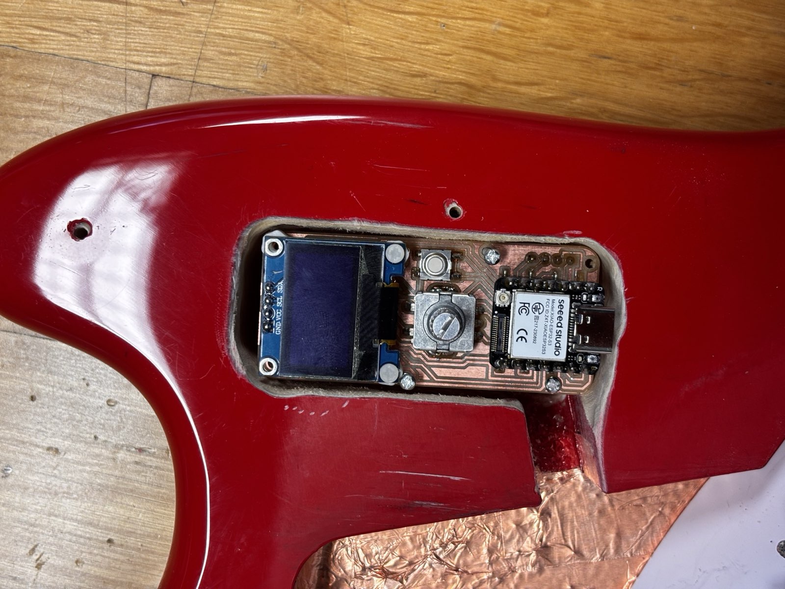 The controller board seated inside the routed pocket in the guitar body, with copper-foil shielding visible on the cavity walls
