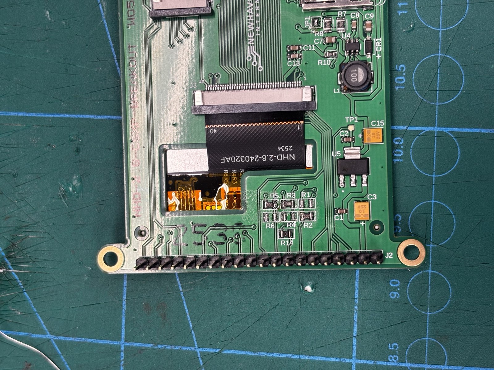Close-up of the back of a green Newhaven NHD-2.8-240320AF TFT breakout board, with reworked solder near the ribbon connector where the interface-select pin was changed
